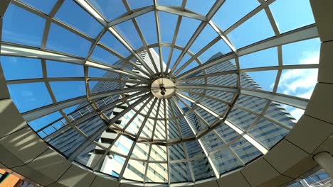 Skyward-view-of-a-modern-glass-dome-structure-with-clear-blue-sky,-architectural-elegance