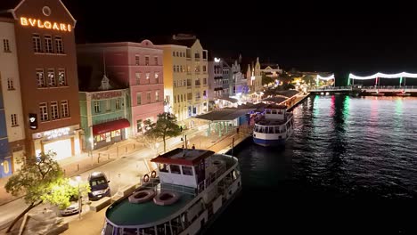 Aerial-dolly-above-ferry-and-Handelskade-buildings-in-evening-at-night-in-Willemstad-Curacao