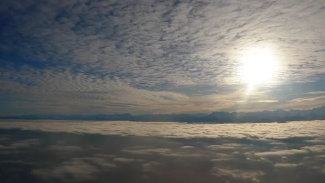 Luftaufnahme-Aus-Dem-Flugzeugfenster:-Sonne-Hinter-Wolken,-Blauer-Himmel,-Spättägige-Schatten