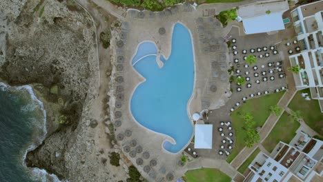 aerial-from-above-view-in-slowmo-footage-of-swimming-pool-luxury-resort-at-palma-de-Mallorca,-Spain-in-sunny-day