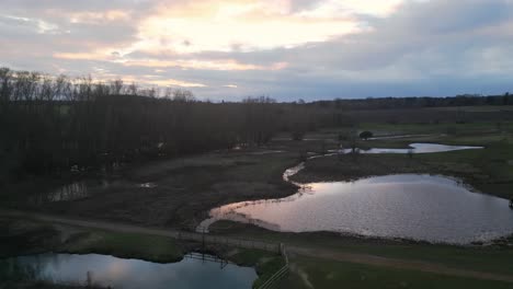 Twilight-descends-on-Southern-Park-in-Norwich,-tranquil-ponds-amidst-grassy-fields,-aerial-shot