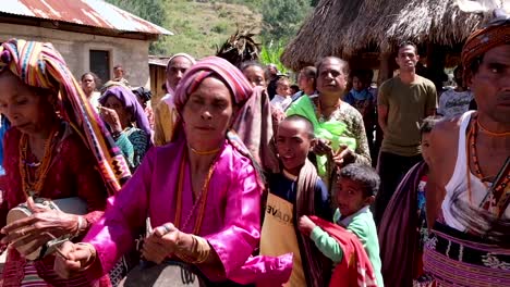 Timorese-community-of-men,-women-and-children-wearing-cultural-clothes-singing-and-dancing-with-instruments-and-weapons-in-East-Timor,-Southeast-Asia