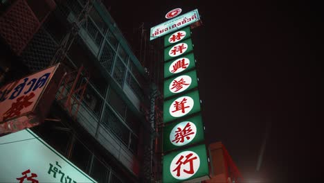 Leuchtende-Chinesische-Leuchtreklame-Hängt-An-Einem-Alten-Gebäude-In-Chinatown,-Bangkok