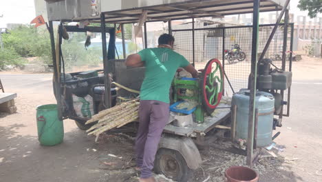 sugarcane-vendor-converts-his-auto-rickshaw-into-mobile-juice-stall,-extracting-fresh-sugarcane-juice-for-parched-passersby,-showcasing-entrepreneurial-spirit-and-innovative-street-side-commerce