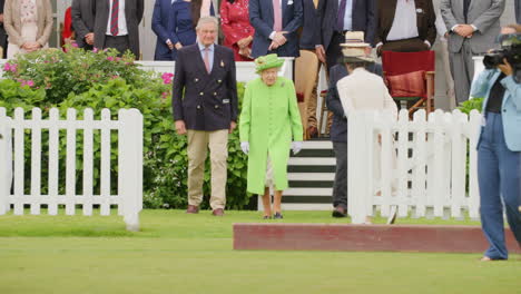 Queen-Elizabeth-II-walks-onto-polo-field-to-present-trophies-whilst-being-photographed-by-press