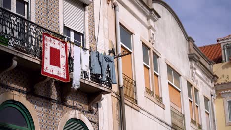 Clothes-drying-on-Clothesline-at-balcony-of-old-building-facade,-Lisbon-City