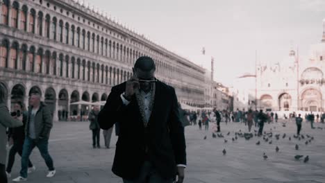 Afrikanischer-Männlicher-Mann-In-Einem-Eleganten-Luxusanzug,-Der-Als-Modemodell,-Umgeben-Von-Touristen-Und-Vögeln,-Cool-über-Die-Berühmte-Piazza-San-Marco-Neben-Dem-Palazzo-Ducale-In-Florenz,-Italien,-Spaziert