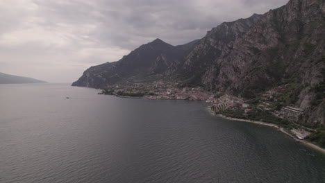 Droneshot-over-the-city-Limone-Italy-on-Lake-Garda-on-a-grey-day-with-mountains-clouds-and-water-LOG