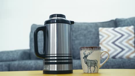 Vacuum-Flask-And-Coffee-Mug-On-Center-Table-In-The-Living-Room