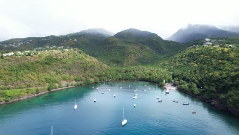 Moored-boats-in-Anse-a-la-Barque-Bay-with-tropical-forest-and-mountains-in-background,-Guadeloupe,-French-Antilles