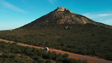 aerial-of-a-van-driving-in-front-of-frenchman-peak-in-cape-legrand-national-park-near-esperance-on-a-sunny-day,-western-australia