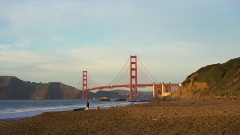 Gente-En-Una-Playa-Frente-Al-Puente-Golden-Gate,-Puesta-De-Sol-En-San-Francisco
