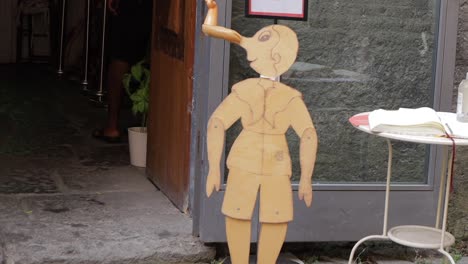 Wooden-cut-out-of-marionette-boy-with-long-twisted-nose-outside-Italian-craft-shop