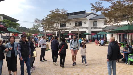 People-enjoy-the-restaurant-area-on-a-sunny-day-in-Ngong-Ping-Village,-Lantau-Island,-Hong-Kong