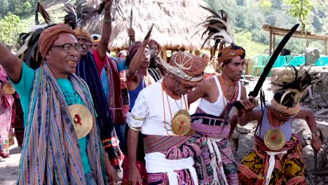 Local-community-elders-and-leaders-wearing-cultural-tais,-mixed-with-modern-clothes-attire,-and-head-wear-with-feathers,-performing-a-traditional-welcome-performance-in-East-Timor,-Southeast-Asia