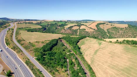 Luftaufnahme-Von-Autos,-Die-Durch-Die-Straße-Entlang-Der-Ländlichen-Felder-Und-Hügel-In-Aveyron,-Frankreich-Fahren