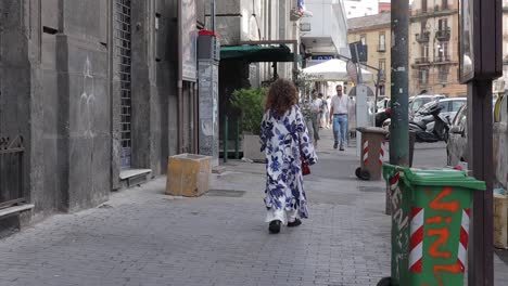 Unrecognisable-woman-in-long-flowery-gown-walks-down-Italian-suburban-street