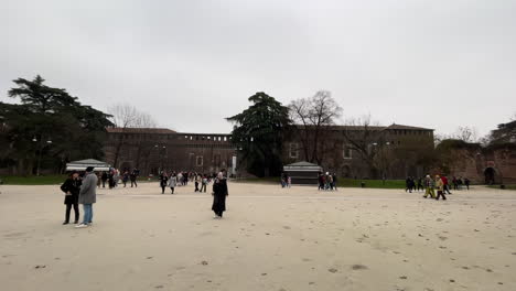 Tourists-walk-outside-of-Castello-Sforzesco,-Sforza-castle-in-Milan,-Italy