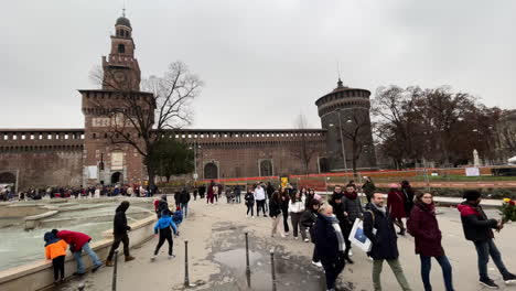 Tourists-walk-outside-of-Castello-Sforzesco,-Sforza-castle-in-Milan,-Italy