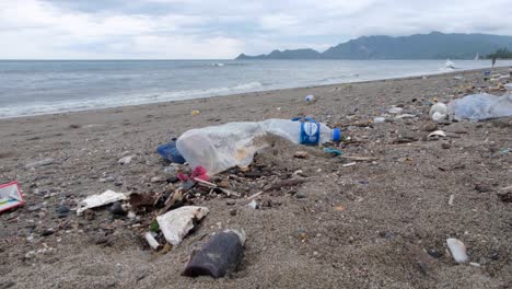 Ocean-plastic-pollution,-trash-and-other-rubbish-washed-ashore-onto-beach-on-the-tropical-island-destination-in-East-Timor,-Southeast-Asia