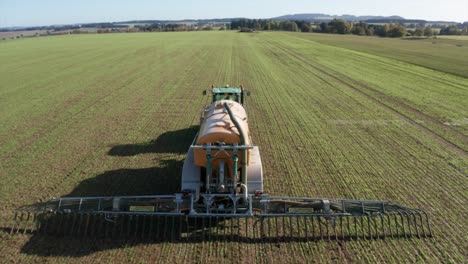 Liquid-manure-spreader-releasing-slurry-on-field-aerial-view