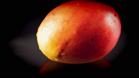 Nasse-Saftige-Mango-Mit-Köstlichen-Wassertropfen-Auf-Saftiger-Roter-Haut-Dreht-Sich-In-Zeitlupe-Auf-Schwarzem-Hintergrund