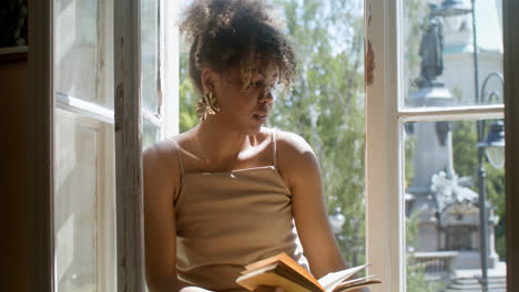 Close-up-view-of-fashionable-african-woman-drinking-lemonade-and-reading-a-book