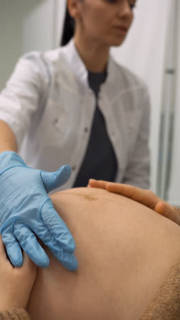 Doctor-palpating-pregnant-woman's-belly