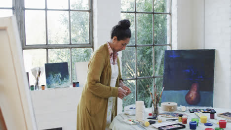 Biracial-female-artist-preparing-paints-in-studio,-slow-motion