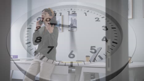 Animation-of-ticking-clock-against-asian-woman-talking-on-smartphone-at-office