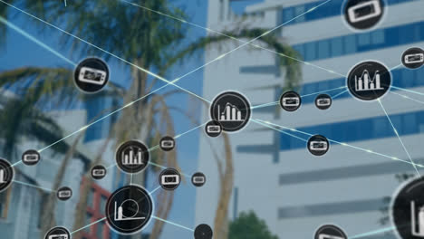 Animation-of-network-of-digital-icons-against-view-of-tall-building-and-palm-tree