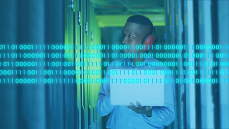 Animation-of-binary-codes,-african-american-engineer-with-headphone-and-laptop-looking-at-servers
