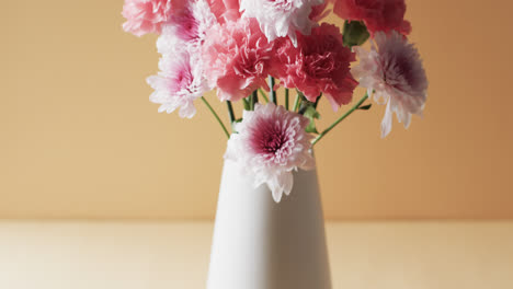 Video-of-pink-flowers-in-white-vase-with-copy-space-on-yellow-background