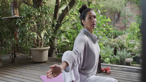 Focused-biracial-woman-practicing-yoga-on-terrace,-slow-motion