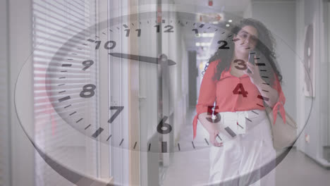 Animation-of-ticking-clock-against-biracial-woman-talking-on-smartphone-walking-in-office-corridor