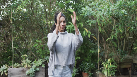 Mujer-Birracial-Enfocada-Practicando-Yoga-En-Un-Jardín-Soleado,-Cámara-Lenta