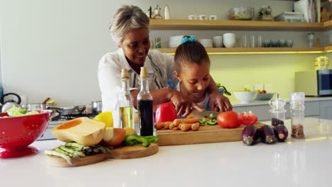Grandmother-assisting-granddaughter-to-chop-vegetables-in-kitchen-4k