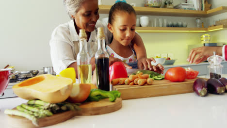 Grandmother-assisting-granddaughter-to-chop-vegetables-in-kitchen-4k