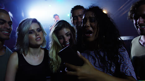 Group-of-friends-reviewing-pictures-on-mobile-phone-at-a-concert-4k