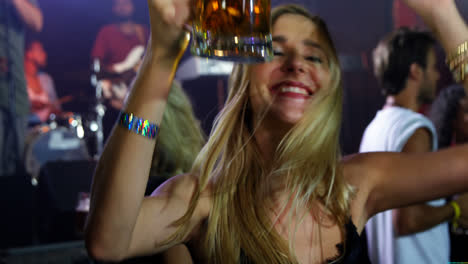 Woman-dancing-with-a-mug-of-beer-at-a-concert-4k