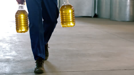 Worker-walking-with-can-of-olive-oils-in-factory