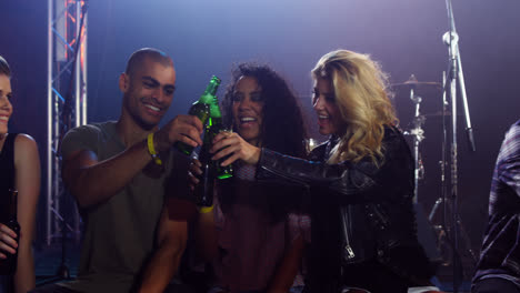Group-of-friends-toasting-beer-bottles-at-a-concert-4k