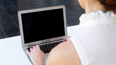 Female-executive-using-laptop-and-digital-tablet-at-desk-4k