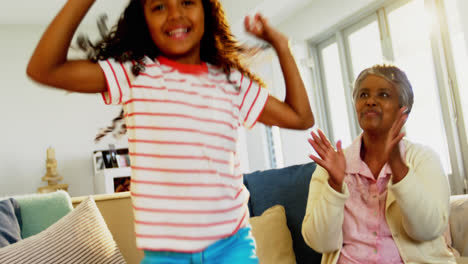 Grandmother-applauding-her-granddaughter-while-dancing-in-living-room-4k