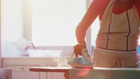 Woman-ironing-shirt-on-ironing-board-in-kitchen-4k
