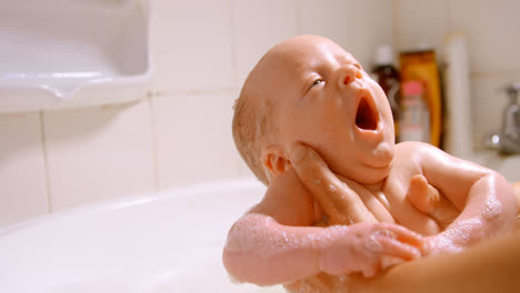 Mother-giving-her-baby-boy-a-bath-in-bathroom-at-home-4k