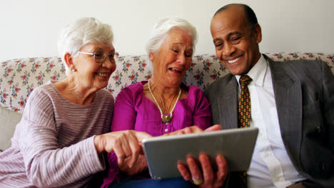 Gruppe-Aktiver-Seniorenfreunde-Gemischter-Herkunft,-Die-Im-Pflegeheim-über-Ein-Digitales-Tablet-Diskutieren,-4k