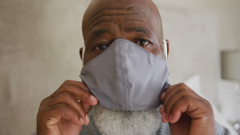 Close-up-of-portrait-of-african-american-senior-man-wearing-face-mask-at-home