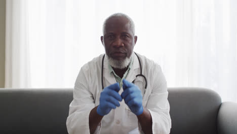 Portrait-of-male-african-american-doctor-showing-how-to-use-face-mask-while-having-a-videocall