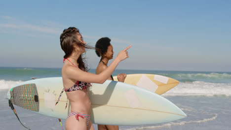 Young-female-friends-walking-with-surfboard-4k